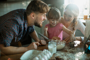 Young family baking together and having fun while being messy in the kitchen
