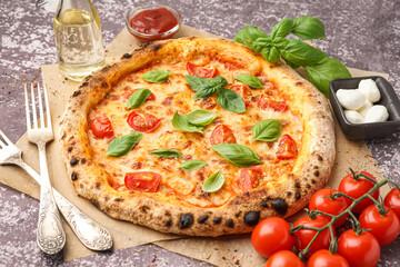 Baking paper with tasty pizza Margarita and bowl of mozzarella on dark table