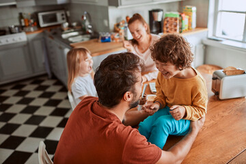 Young family having breakfast together and being messy in the kitchen