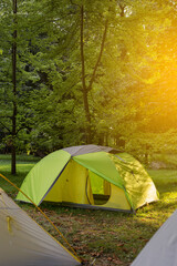 Camping tent standing on grass in forestduring sunlight