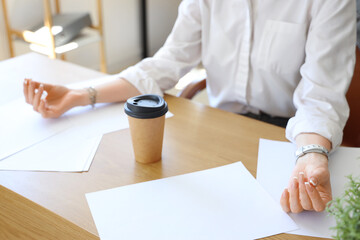 Young businesswoman meditating in office, closeup