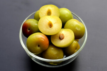 Fresh green plum fruit on dark background.