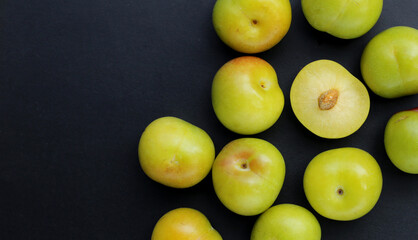 Fresh green plum fruit on dark background.