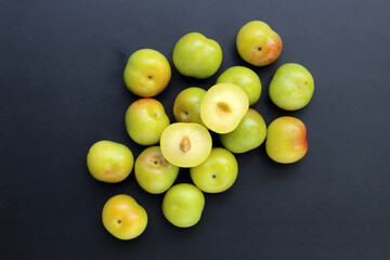 Fresh green plum fruit on dark background.