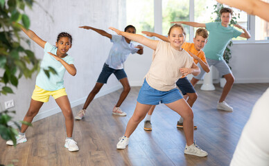 Positive cheerful children studying modern style dance in class indoors