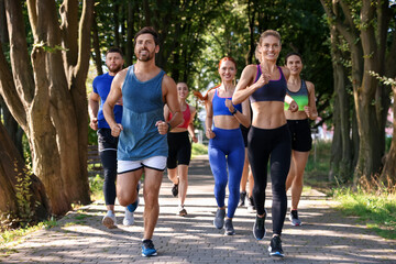 Group of people running in park on sunny day
