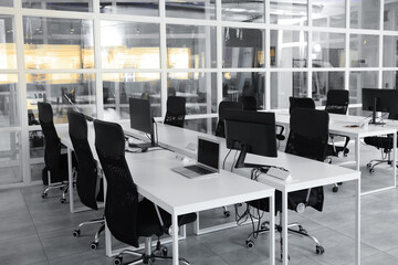 Stylish interior of open plan office. Workspace with computers, tables and chairs