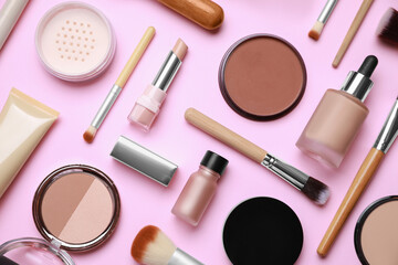 Face powders and other decorative cosmetic products on pink background, flat lay