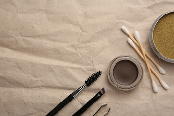Flat lay composition with eyebrow henna and tools on crumpled paper. Space for text