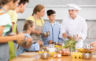 Cooking class, culinary, food and people concept - happy group of children and male chef cook cooking in kitchen