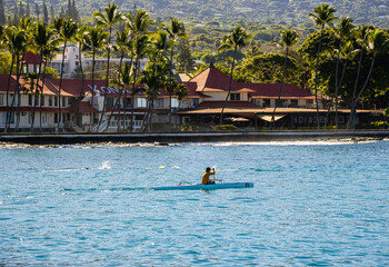 Outrigger Canoe Paddler and The Waterfront Of Kailua-Kona on Kailua Bay, Kailua-Kona, Hawaii...