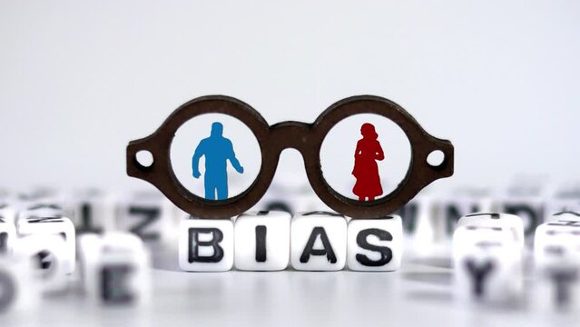 Miniature glasses and white cube with BIAS on it. The concept of social prejudice against men and women.
