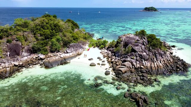 couple on the beach of Kla Island in front of Koh Lipe Island Southern Thailand, turqouse colored ocean and white sandy beach with a kayak at Ko Lipe on a sunny day at Koh Lipe