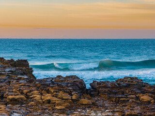 Fototapeta na wymiar Ocean sunrise with wave amd pastel coloured sky