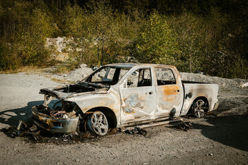 A burned out Dodge pick up truck lies abandoned beside a gravel road in rural British Columbia, Canada.