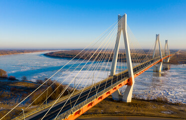 Aerial view of multispan cable-stayed Murom Bridge across ice covered Oka river on sunny winter day, Vladimir region, Russia.