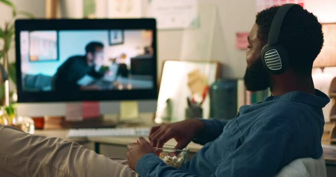 Computer, web vlog and man watching movie with snacks and food in home office. Relax, internet and African male person with film subscription app and tech with headphones listening to online video