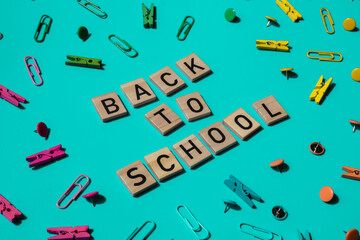 Educational greeting announcement for students and teacher. Saying BACK TO SCHOOL text on wooden blocks on creative vivid background with stationery supplies around. Concept of new school year Top