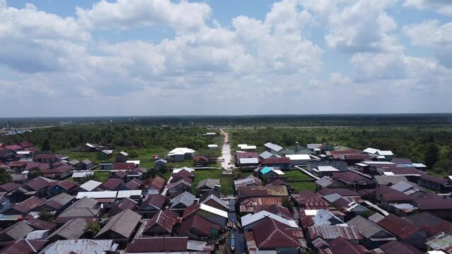 Aerial view of the City on the river's banks with the activity of boats speeding over the river. Pangkalan Bun, central kalimantan, Indonesia - 25 August 2023