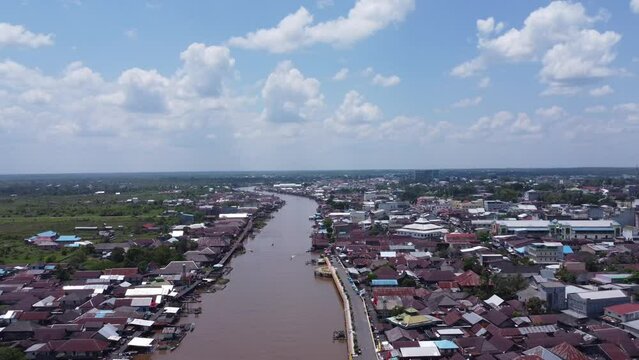Aerial view of the City on the river's banks with the activity of boats speeding over the river. Pangkalan Bun, central kalimantan, Indonesia - 25 August 2023