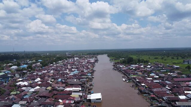 Aerial view of the City on the river's banks with the activity of boats speeding over the river. Pangkalan Bun, central kalimantan, Indonesia - 25 August 2023