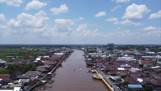 Aerial view of the City on the river's banks with the activity of boats speeding over the river. Pangkalan Bun, central kalimantan, Indonesia - 25 August 2023