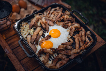 Fried eggs and grilled pork in a camping pan