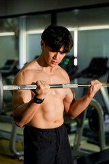 Closeup Asian handsome man with perfect body playing weight training at fitness center.