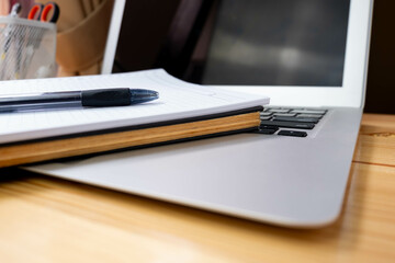 Image of workplace in office room without people with open laptop, pencil and notebook lying on wooden desk