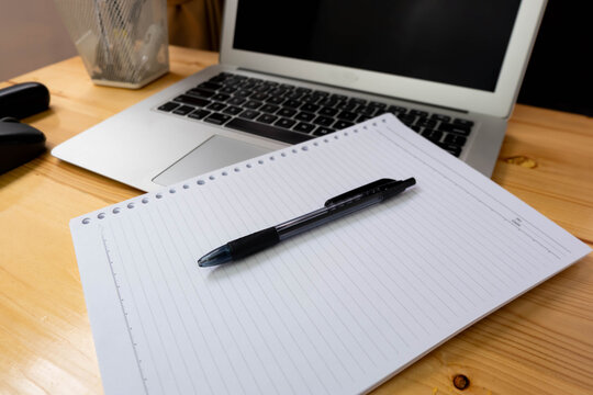 Image of workplace in office room without people with open laptop, pencil and notebook lying on wooden desk