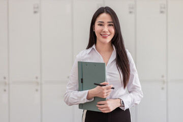 Image of young asian woman, company worker smiling and holding documents of contracts with...