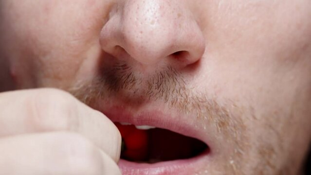 In a close-up shot, a man puts a mini hot red pepper of "The Star of Turkey" variety into his mouth and chews it.
