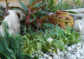 Beautiful landscaping design to decorate the garden with green plants, stones and clay jugs