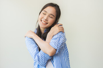 Smiling positive, hug self care happy asian young woman hands hugging herself shoulders, enjoy...