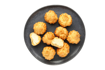 Homemade profiteroles with cream on dark plate isolated on white background. Fresh baked golden profiterole.