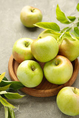 Ripe green apples with green leaves on grey concrete background. Vertical photo