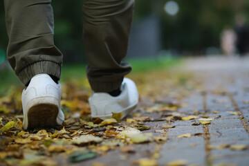 Feet sneakers walking on fall leaves Outdoor with Autumn season nature on background Lifestyle Fashion trendy style