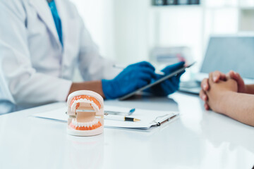 Teeth treatment talk, dentist and patient engaging in a discussion with a model, dental consultation exemplifies patient-centered dentistry, emphasizing personalized care and informed choices.