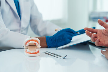 Teeth treatment talk, dentist and patient engaging in a discussion with a model, dental consultation exemplifies patient-centered dentistry, emphasizing personalized care and informed choices.