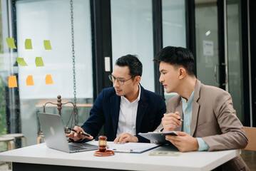 Business and lawyers discussing contract papers with brass scale on desk in office. Law, legal services, advice,  justice and law concept ..