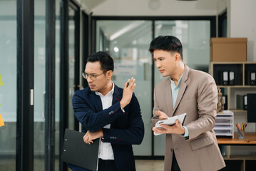 Furious two Asian businesspeople arguing strongly after making a mistake at work in modern office..