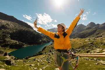 Person climbing in high mountains with yellow jacket rope and helmet in nature, confidence and risk, safety, person called by mobile phone in the mountains, taking photos, taking selfie