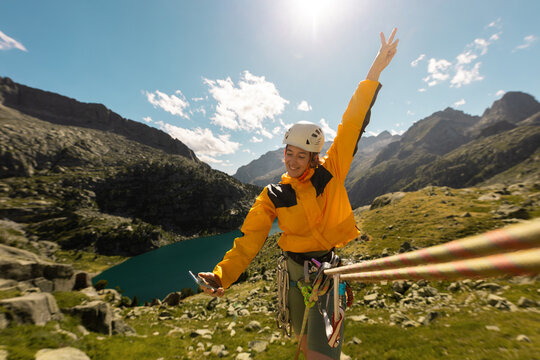 Person climbing in high mountains with yellow jacket rope and helmet in nature, confidence and risk, safety, person called by mobile phone in the mountains, taking photos, taking selfie