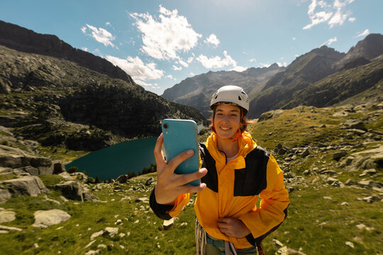 Person climbing in high mountains with yellow jacket rope and helmet in nature, confidence and risk, safety, person called by mobile phone in the mountains, taking photos, taking selfie