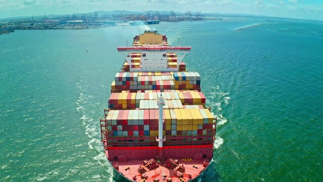 Aerial front view of a container ship sailing at the sea for transportation.