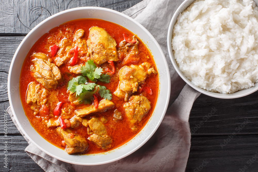 Wall mural Asian chicken curry in a sauce consisting of onion, ginger, lemongrass, pepper, garlic and tomato close-up in a bowl on the table. Horizontal top view from above