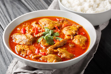 Spicy Burmese chicken curry in a sauce consisting of onion, ginger, lemongrass, pepper, garlic and tomato close-up in a bowl on the table. Horizontal