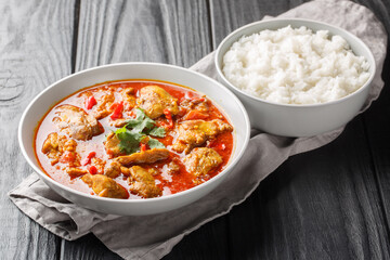 Homemade chicken curry in red spicy sauce served with jasmine rice close-up in a bowl on the table. Horizontal