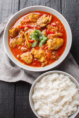 Burmese Curry juicy, tender chicken is bathed in a spicy sauce served with rice closeup on the wooden table. Vertical top view from above