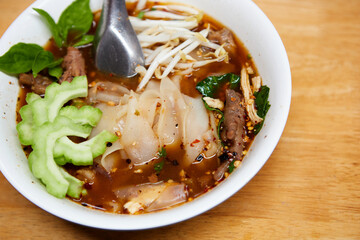 Wide rice noodles with braised chicken meat in a bowl